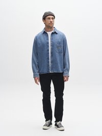 Helehall sinine teksasärk esitasku ja logoga; kombineeritud mustade teksade ning must-valgete tossudega. Kannatud halli kootud nokamütsiga.