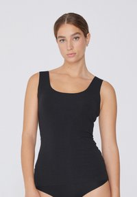 Débardeur noir avec un col round, design ajusté et texture douce. Construction simple et sans couture pour une silhouette épurée.