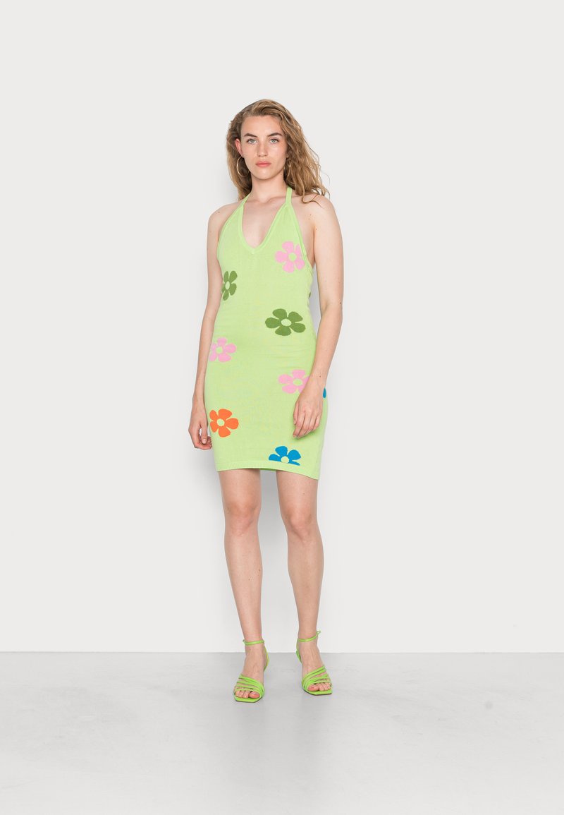 Robes halter tricotées en vert clair avec des motifs floraux multicolores en rose, orange, bleu et vert ; assorties avec des sandales vertes à lanières.