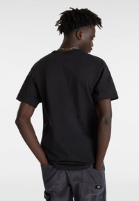 T-shirt en coton noir à manches courtes, design basique, col rond et coupe décontractée, vu de dos.