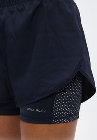 Σκούροι ναυτικοί αθλητικοί σορτς με πολυστρωματική σχεδίαση, που διαθέτουν εσωτερικό στρώμα με μικρές λευκές πουά και το κείμενο "ONLY PLAY".