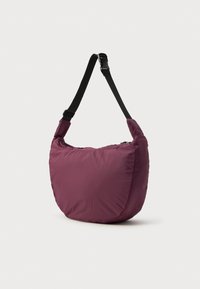 Bolso blando y esponjoso en un profundo burdeos, con una correa negra ajustable. Su forma redondeada ofrece un diseño informal con una textura suave.