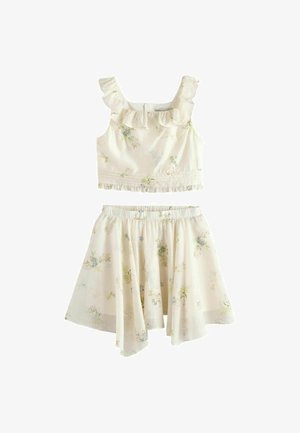 Krémový dvojdielny outfit s volánikovým crop topom bez rukávov a zodpovedajúcou rozšírenou sukňou, obe s jemným kvetinovým vzorom.