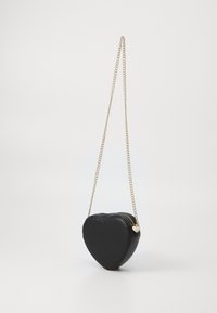 Borsa a forma di cuore nera realizzata in materiale sintetico con texture trapuntata. Presenta una tracolla in catena dorata e chiusura con zip.