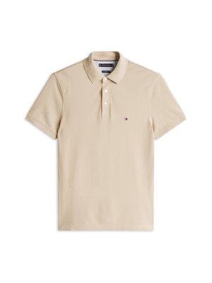 Beigen värinen lyhythihainen poolopaita, jossa on kaulus, kolmen napin lista ja pieni Tommy Hilfiger -logo vasemmassa rinnassa.