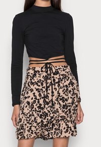 Mustat pitkät hihat, lyhyt toppi korkealla kauluksella. Vaaleanbeige hame, jossa on musta leopardi kuvio ja kerrostetut röyhelöt, vyötäröllä solmimisominaisuus.