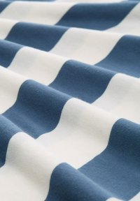 Gestreifter Stoff in abwechselndem Marineblau und Weiß, mit weicher Textur und sanften Wellen, die das Muster und das Material betonen.