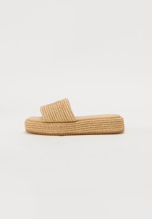 Beige vævede platforme slidesandal med bred rem og tekstureret sål på en enkel lys baggrund.