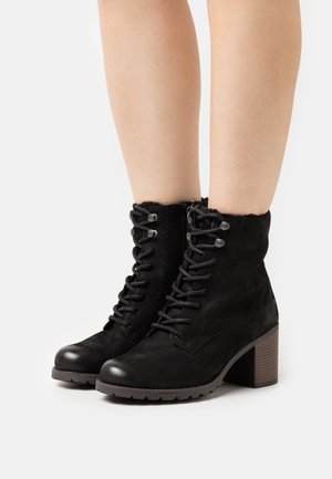 Black suede ankle boots with a lace-up design, round toe, mid-height block heel, and textured sole. Accented with metal eyelets.