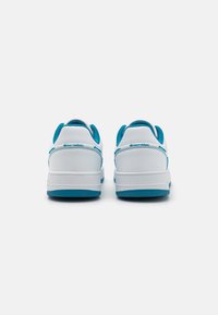 Vita sneakers med turkosa accenter, texturerat tyg vid kragen, slät läderkropp, gummisula och förstärkt hälstöds.