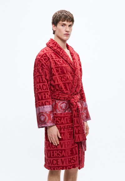 Červený župan z froté látky s celoplošným vzorem loga Versace, vyšívanými detaily, šálovým límcem a odpovídajícím opaskem.