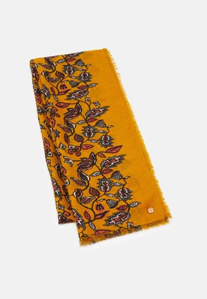 Musztardowo-żółty szalik z czarnym, czerwonym i białym kwiatowym wzorem oraz frędzlami na brzegach, ułożony płasko na białym tle.