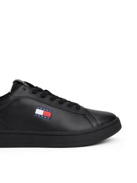 Čierne nízke tenisky s čiernymi šnúrkami a nášivkou loga Tommy Jeans na boku, vystavené na bielom pozadí.