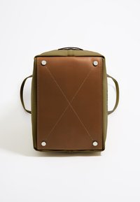 Olijfgroene tas met een bruine leren basis, voorzien van zilverkleurige hardware, kruissteeknaden en twee zijhandvatten voor het dragen.