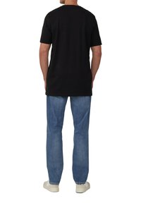 Zwarte katoenen t-shirt met ronde hals, gedragen met blauwe denim jeans en witte sneakers, met een ontspannen pasvorm en rechte snit.