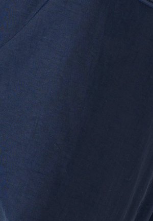 Gros plan sur un tissu bleu foncé avec un fin nervurage diagonal et une couture cousue dans le coin supérieur gauche.