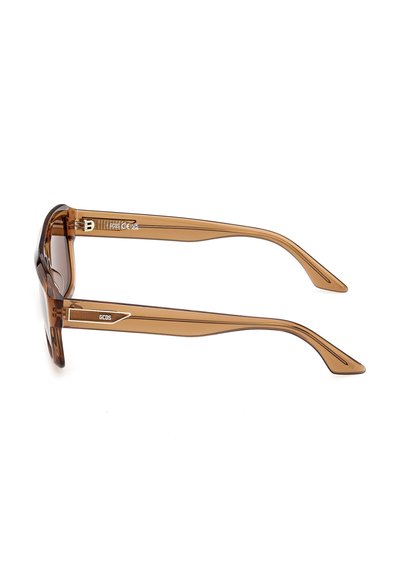 Lunettes de soleil rectangulaires translucides marron avec des branches épaisses portant un logo GCDS blanc sur le côté.