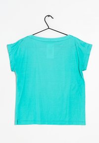 T-shirt turchese a maniche corte con vestibilità ampia, scollatura rotonda e spacchi laterali. Realizzato in tessuto leggero, appeso a un gancio nero.