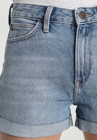 Ljusblå denimshorts med en slitna finish, med upprullad fåll, fem fickor och en märkesknapp i metall.