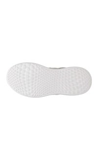 Biała podeszwa sneakersów z heksagonalnym wzorem trakcyjnym, z lekkim zakrzywieniem na czubku. Miękki, teksturowany materiał gumowy.