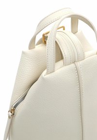 Valge nahast käekott, millel on tekstureeritud viimistlus, lukuga sulgemine, kaks ülemist käepidet ja struktuurne kuju kuldse tooniga riistvaraliste detailidega.