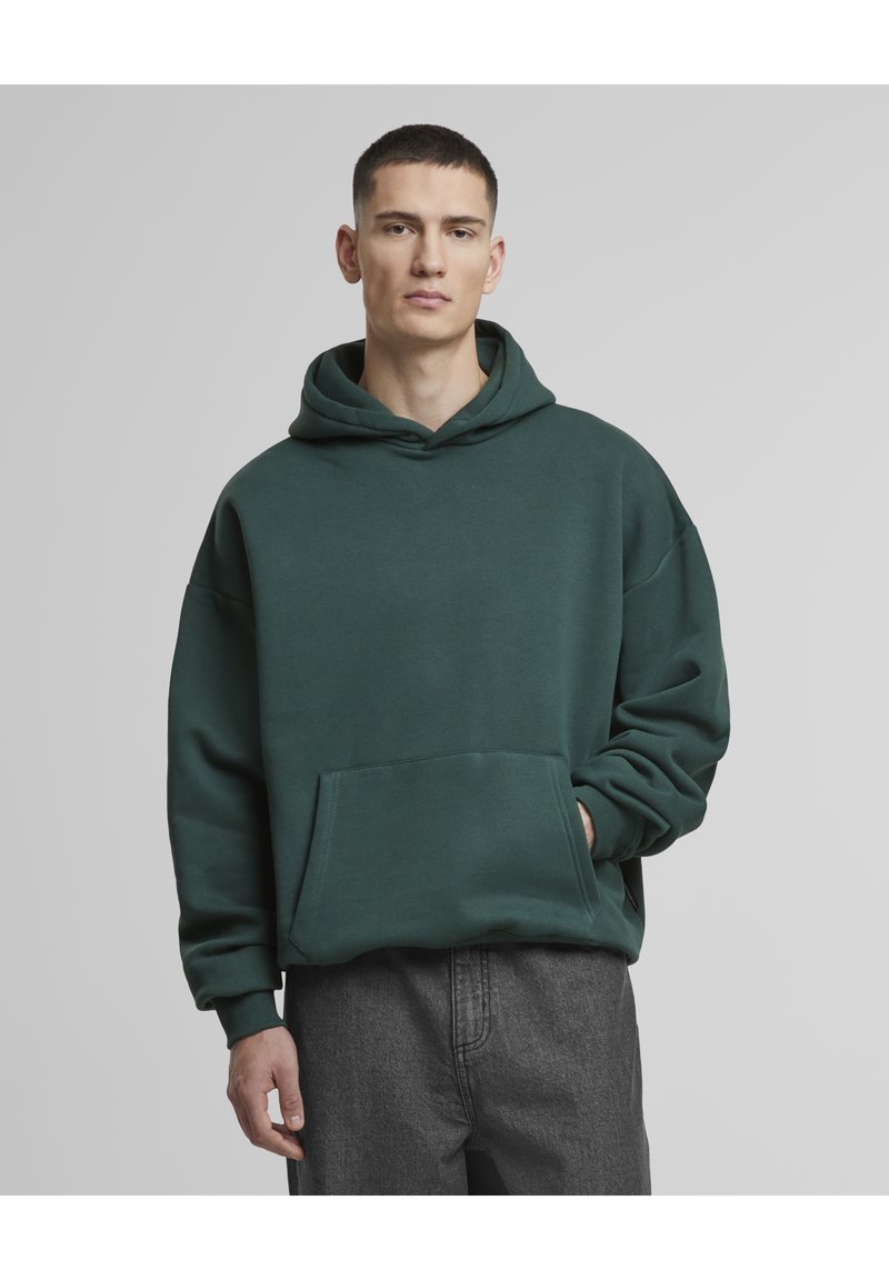 Grønn hettegenser med kengurulomme, justerbar snorhette og ribbestrikkede mansjetter. Myk, teksturert stoff med løs passform.