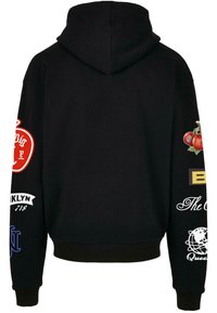 Hanorac negru cu glugă, de lungime scurtă, decorat cu broderii colorate de diferite modele pe ambele mâneci. Textura materialului este moale.