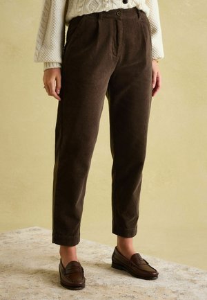 Brown corduroy trousers with a high waist, tapered leg, front pleats, and side pockets, paired with brown loafers. Texture is ribbed.