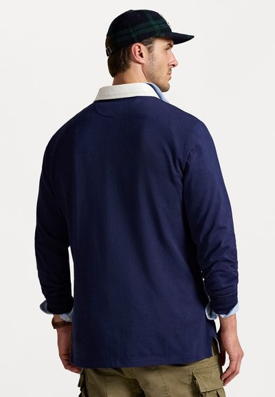 Polo shirt navy cu mâneci lungi, cu guler alb și guler interior albastru. Prezintă o textură fină, o margine dreaptă și slituri laterale.