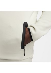 Jasnoszary sweatshirt z czarnym detalem kieszeni na suwak przy mankiecie, o gładkiej fakturze i luźnym kroju.