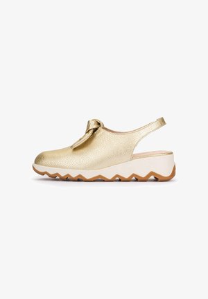 Zapato slingback con textura dorada, lazo anudado en la parte superior, suela blanca gruesa en zigzag y una plantilla marrón para mejor agarre, vista lateral sobre fondo blanco.