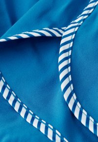 Blue fabric with a smooth texture, featuring white and blue striped accents along the edge, highlighting a curved seam.