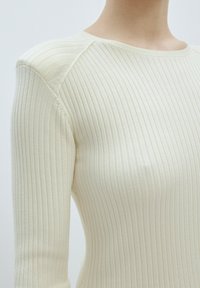 Cremfarbener, gerippter Strickpullover mit Rundhalsausschnitt und langen Ärmeln, weicher Textur und dezenten vertikalen Linien.