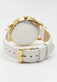 Witte leren strap horloge met een gouden roestvrijstalen kast en een doorzichtige glazen achterkant die het merk "ESPRIT" toont. Zilveren details op de strap.