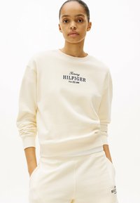 Crème kleurige sweatshirt met een ronde hals, ribgebreide manchetten en geborduurd logo "Tommy HILFIGER" in marineblauw. Zachte, gestructureerde stof.