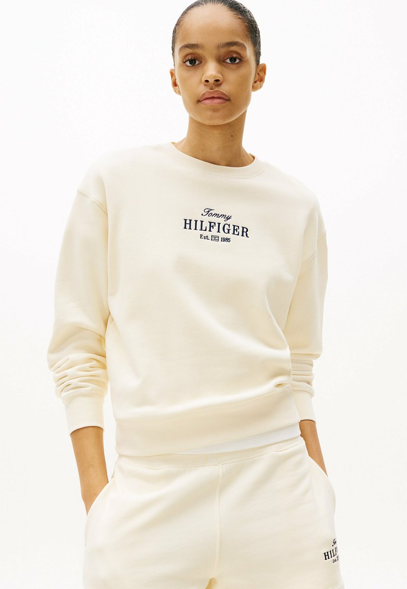 Crème kleurige sweatshirt met een ronde hals, ribgebreide manchetten en geborduurd logo "Tommy HILFIGER" in marineblauw. Zachte, gestructureerde stof.