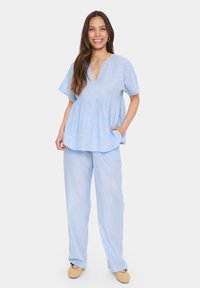 Light blue two-piece outfit with a flowy top featuring a V-neck and short sleeves, paired with straight-leg pants, both displaying subtle vertical stripes.