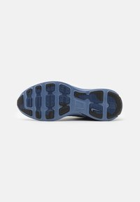Semelle d'une chaussure de sport bleue et noire avec une bande de roulement en caoutchouc texturé et un petit logo Nike près du talon.