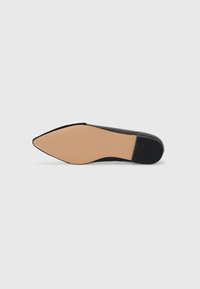 Sorte spissese sko med glatt overdel, flat såle og matt finish. Sålen er beige med en subtil tekstur.