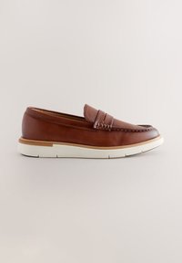 Mocassin penny en cuir marron avec semelle en caoutchouc blanche sur fond neutre, vue latérale montrant les coutures et le détail moc toe.