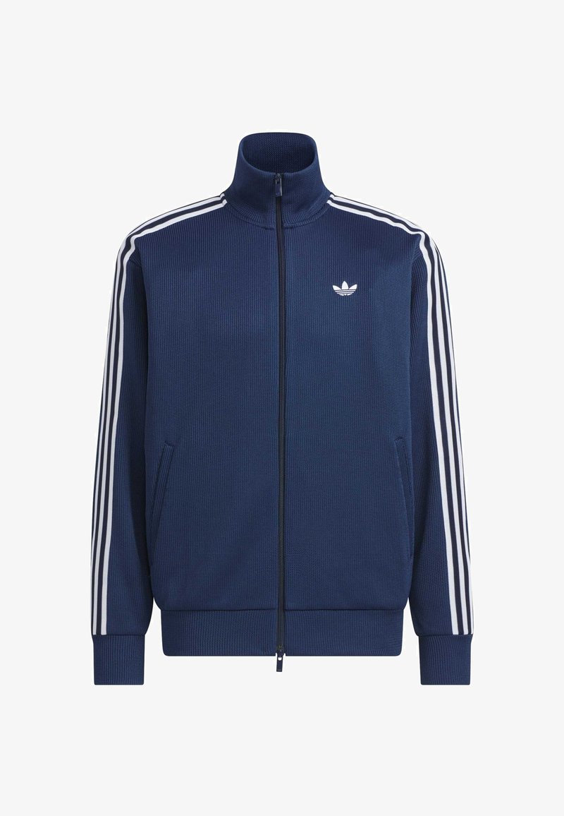 Giacca sportiva con cerniera blu navy con tre strisce bianche sulle maniche e logo Adidas bianco sul petto, polsini e orlo a coste.