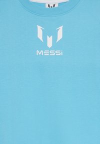Lys blå hettegenser med rund hals, med design av en hvit logo som inkluderer teksten "MESSi" og et stilisert emblem over.