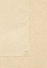 Beige gebreide trui met een textuurpatroon, een gladde sectie en een kleine ronde logoknop in de onderste hoek.