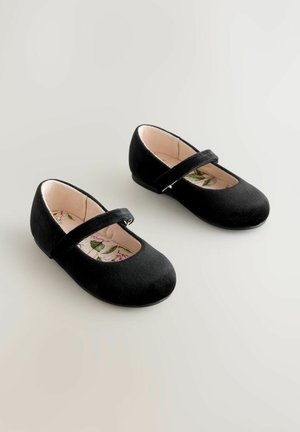 Črne baletne balerinke iz semiša z zaobljenim prstom in trakom čez nart. Notranjost ima cvetlični vzorec na svetli podlagi.