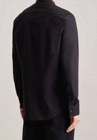 Camicia nera a maniche lunghe con taglio dritto, tessuto liscio, polsini con bottoni e una sottile lucentezza sulla schiena.