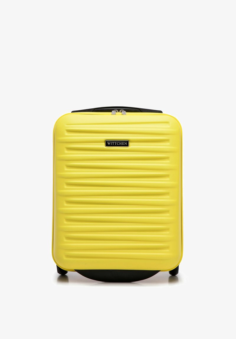 Žlutý tvrdý kufr s texturovaným povrchem, žebrovaným designem, černými akcenty, horním madlem a zipovým uzávěrem. Značkové logo je výrazně zobrazeno.