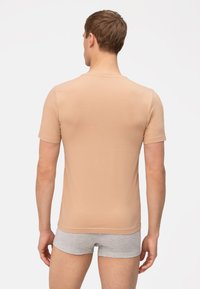 Strak, kort mouwen t-shirt van lichtbeige stof, met een ronde hals en een gladde textuur. Gedragen met grijze shorts.