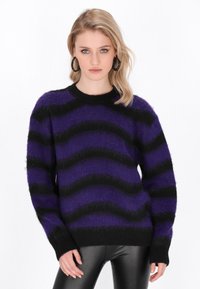 Maglione a righe viola e nere con texture soffice, scollatura rotonda e maniche lunghe; indossato con pantaloni neri attillati.