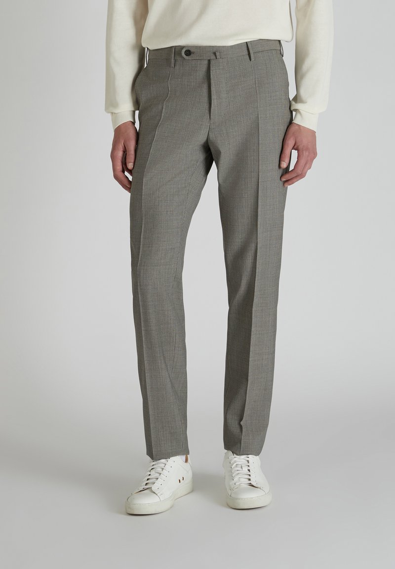 Grijze geprinte pantalon met een getailleerde pasvorm, voorzien van een knoopsluiting en zijzakken, gecombineerd met witte sneakers op een effen achtergrond.
