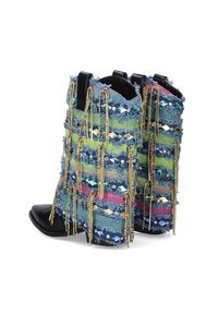 Botines de denim con tela deshilachada de múltiples colores, adornados con cuentas y acentos metálicos, que presentan una punta negra y un tacón alto.